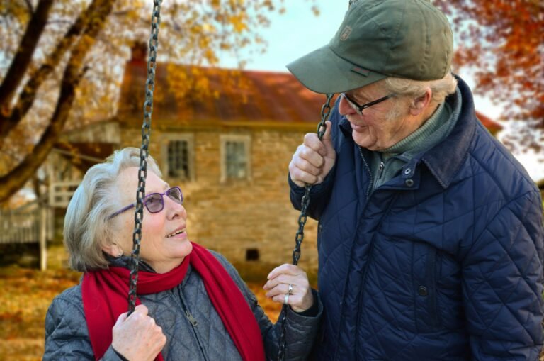 A happy elderly couple sharing a joyful moment on a swing in autumn setting. Freedom Square of Seminole