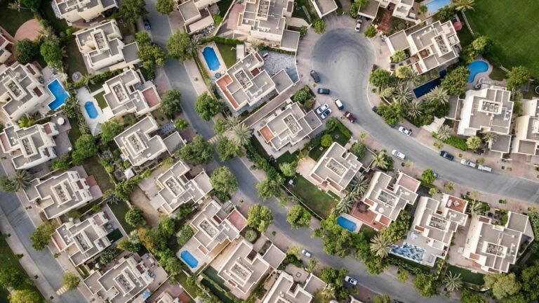 Explore a stunning aerial view of a residential area in Dubai with lush greenery and swimming pools. London Properties Data Breach